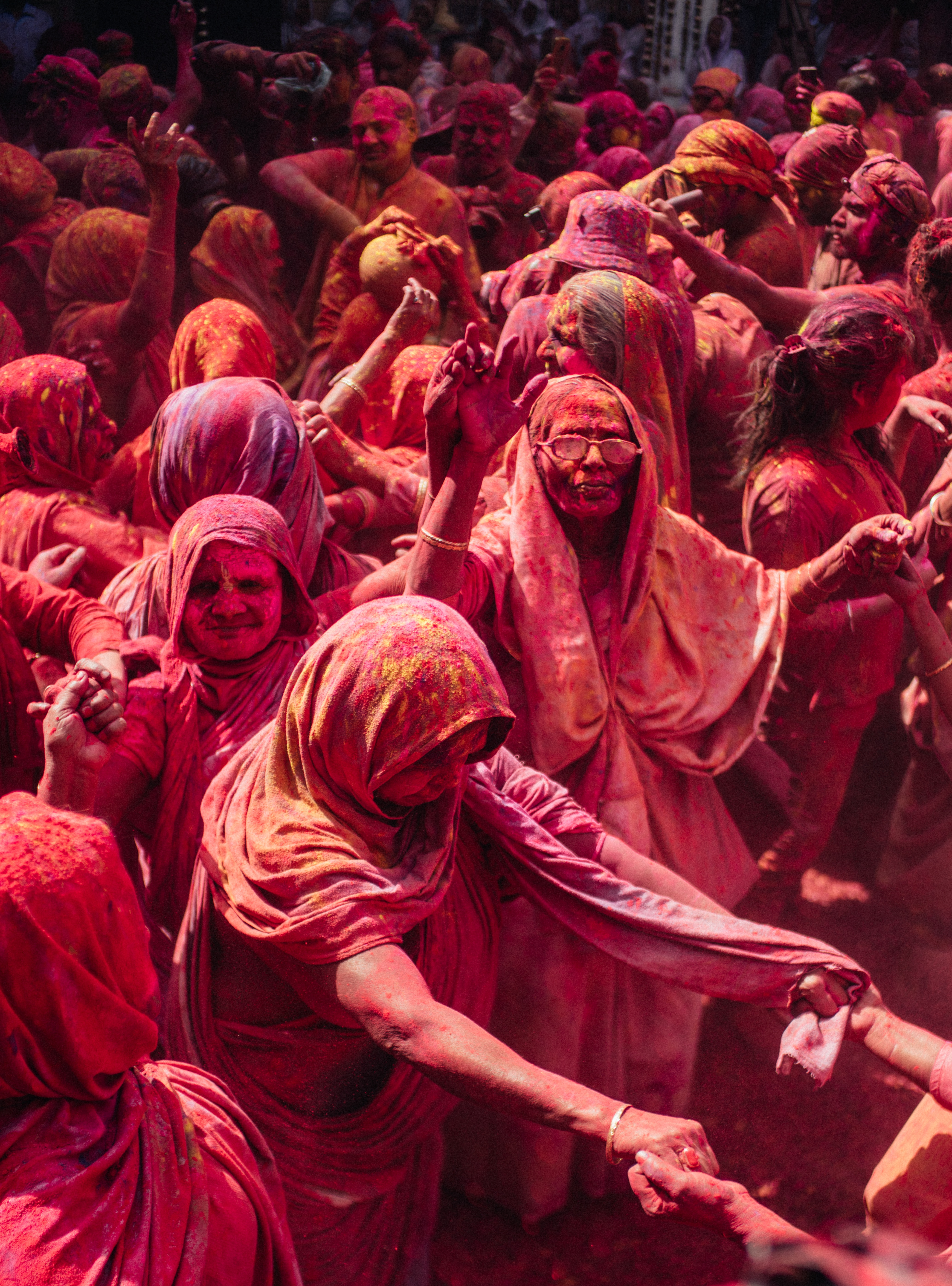 Crowd of Women Celebrating Holi in India Covered in Red and Orange Powdered Paints.