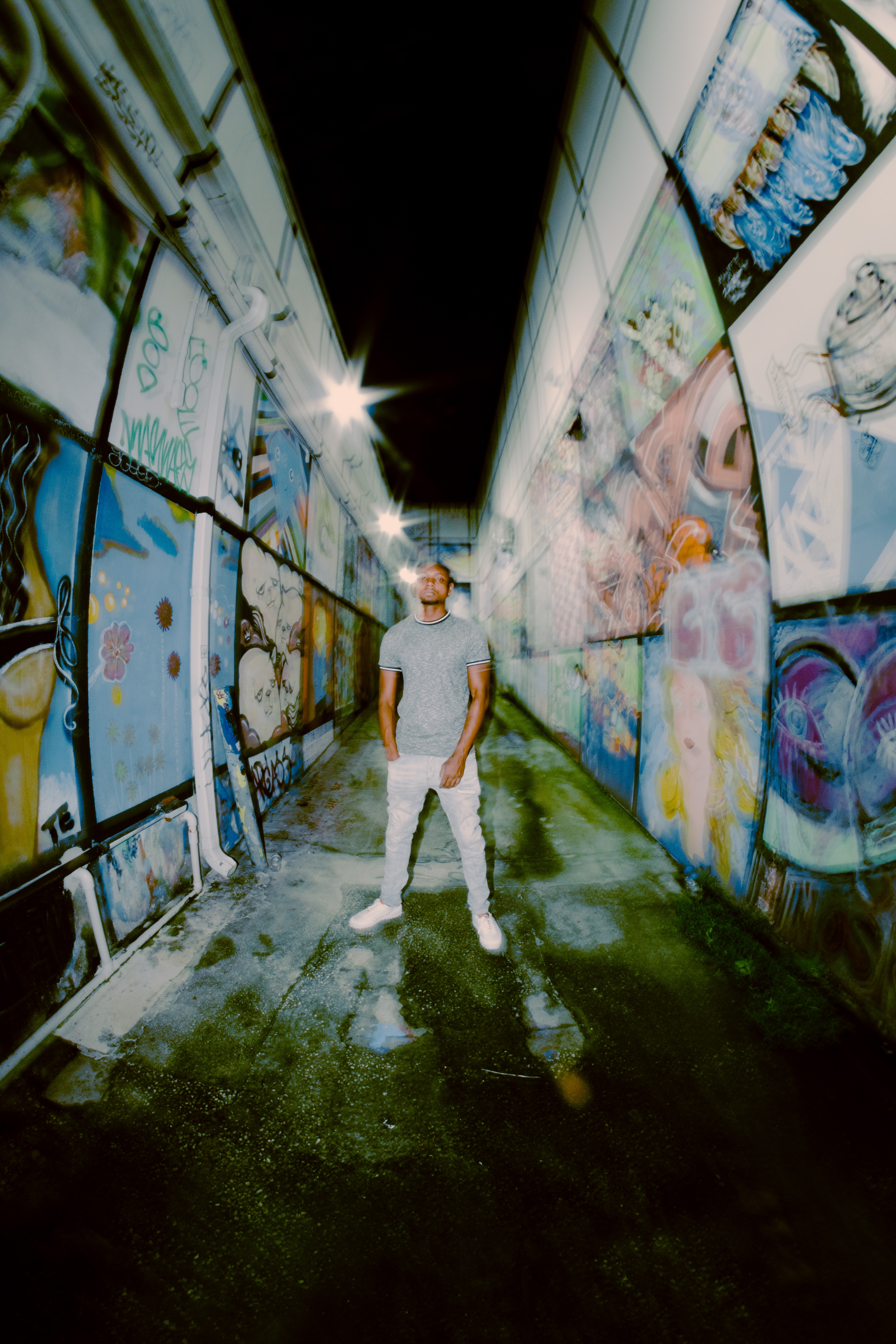 Blurry image of man in the center of the photo surrounded by various murals.