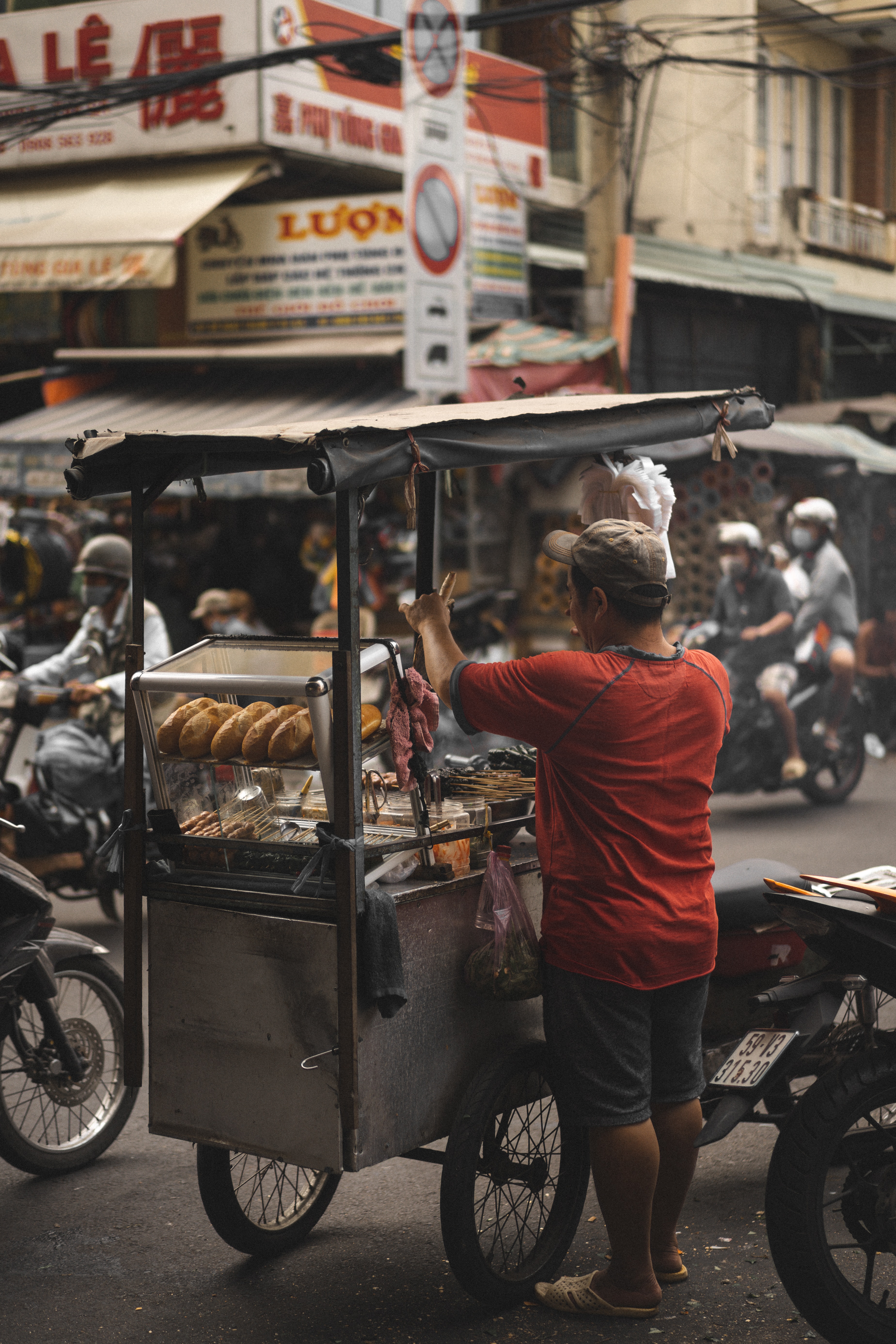 Man grilling meat at a cart in a city street.