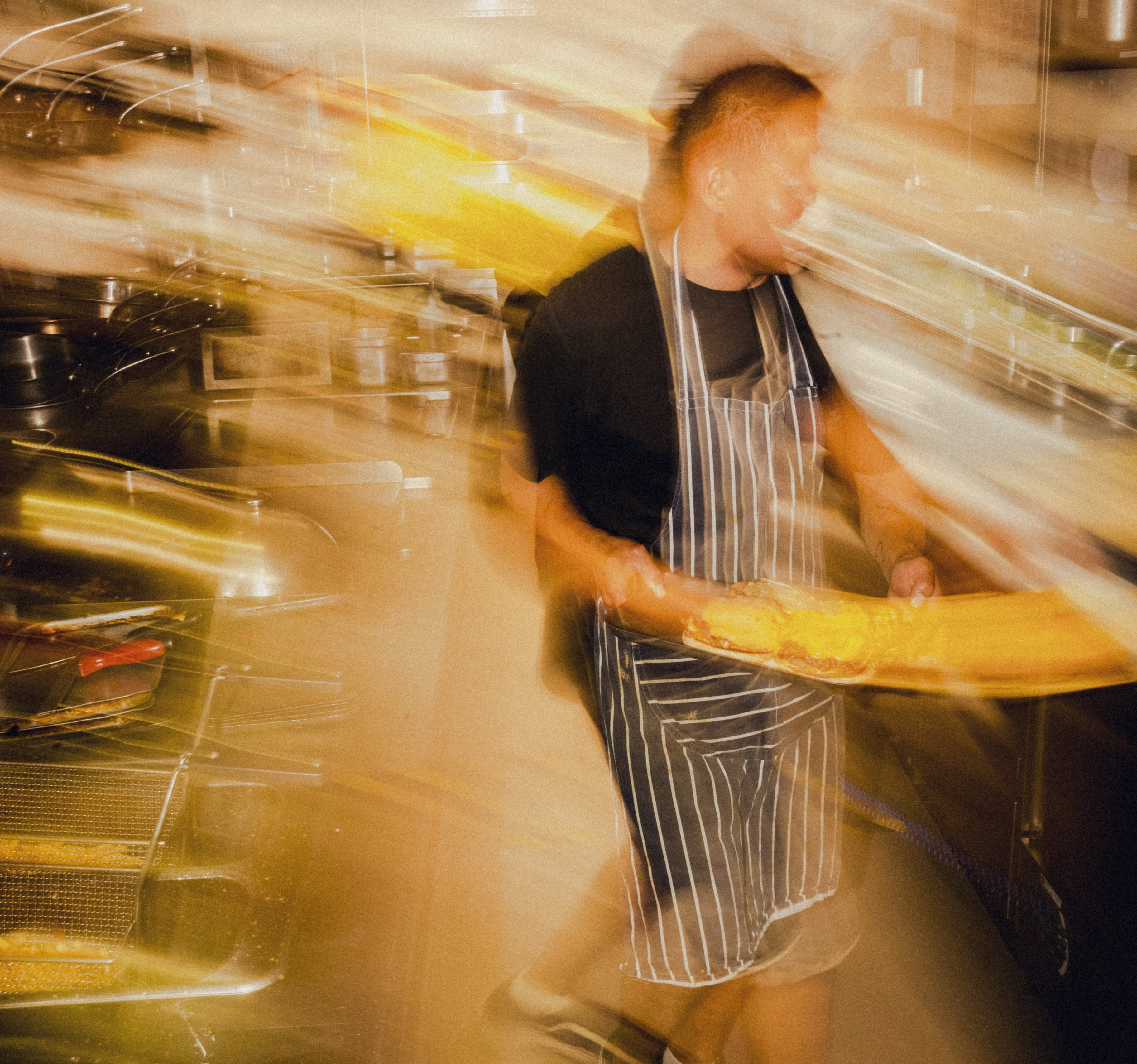 Blurry image of a man holding a plate in a kitchen.