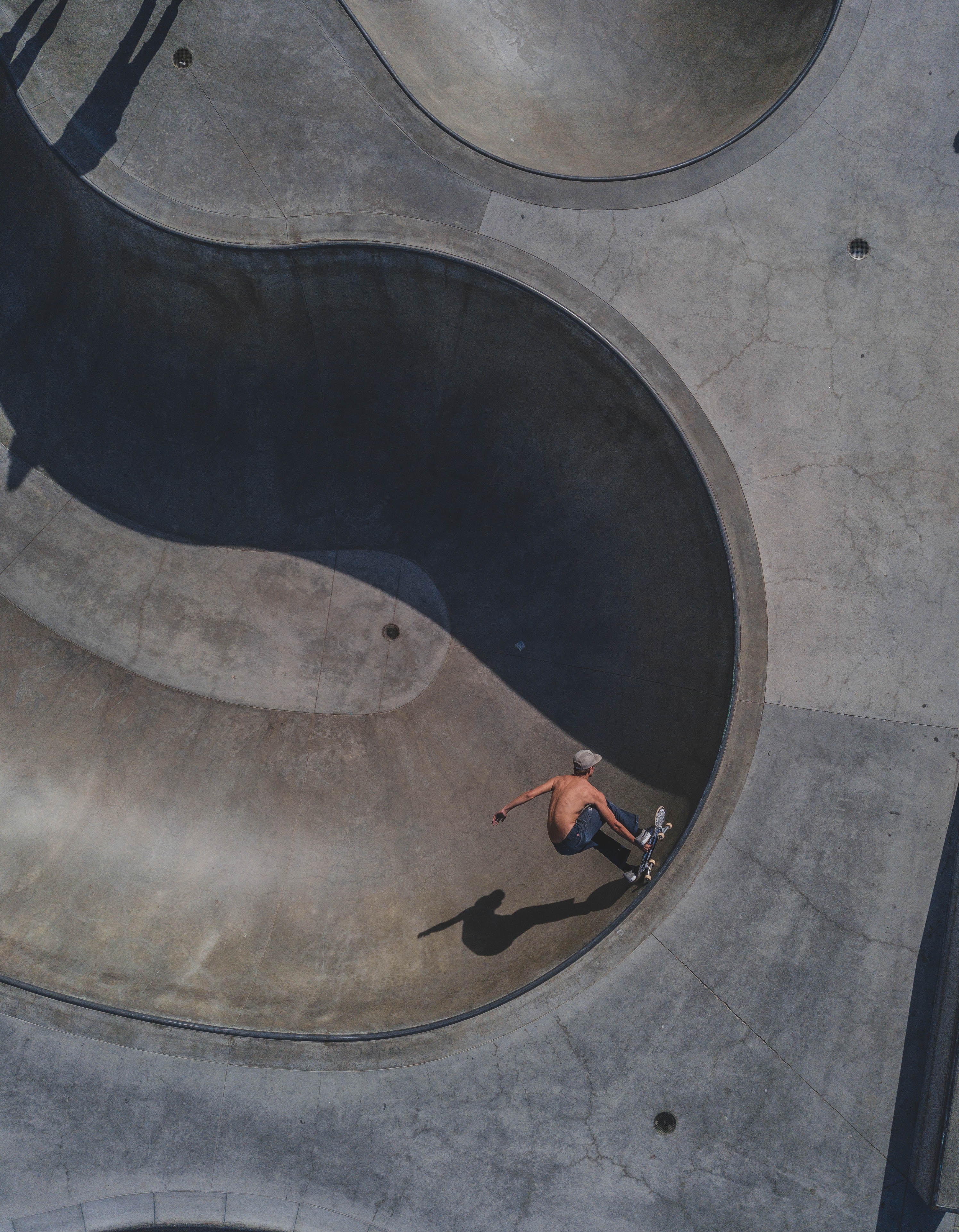 Arial view of a shirtless skater skating in a bowl.